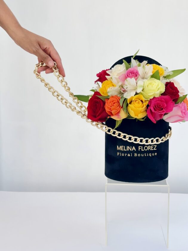 Delicacy and glamour are inside this little black velvet box with its golden strap accompanied by roses (multicolored) and astromelias (white). Ideal to accompany a dinner table.