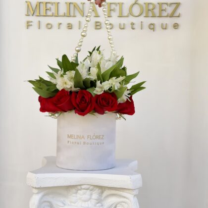 Small white velvet box with a beautiful pearl arrangement in red roses and white astromelias. It is a classic must-have