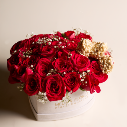 White heart in red roses and baby breath accompanied by three strawberries covered in white chocolate, chips and gold dust.