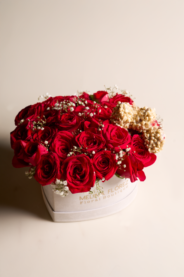 White heart in red roses and baby breath accompanied by three strawberries covered in white chocolate, chips and gold dust.